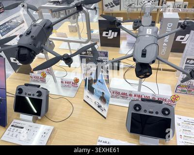 DJI Mini and Air series drones on display with price tags and controllers in a Japanese shop. Fukuoka, Japan - October 30, 2025. Stock Photo