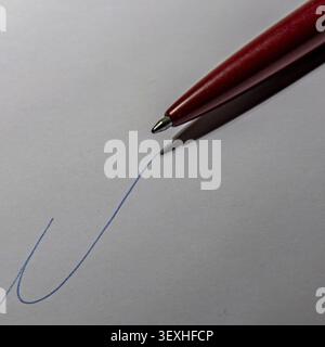 Pen writing blue ink on white paper sheet Stock Photo