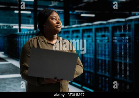 IT expert provides technical support from a data center using a headset while troubleshooting client server issues. Stock Photo