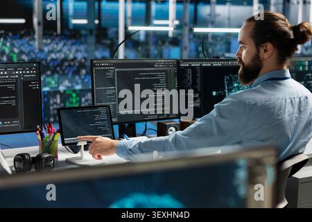 System administrator uses a digital tablet in a data center to deploy software updates, configure hardware, and support reliable operations. Stock Photo