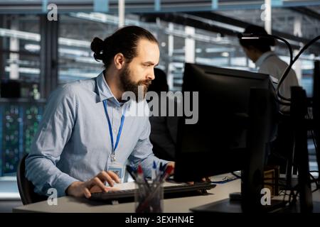 System administrator uses a desktop computer in a data center to manage AI systems and optimize server infrastructure. Stock Photo