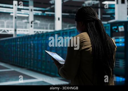 Computer scientist works with a computer workstation in a server room to support artificial intelligence systems. Stock Photo