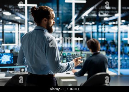 Data center programmers use a digital device in a data center to support automation monitoring and reliable server workflows. Stock Photo
