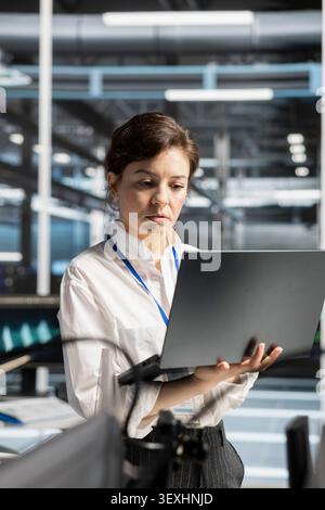 IT expert uses a laptop computer in a data center to manage AI systems and optimize server infrastructure. Stock Photo