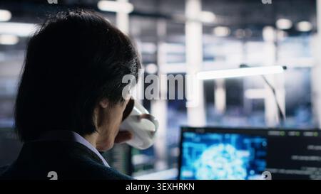Software developer programs on a computer workstation in a server farm with generative AI assistance. Stock Photo