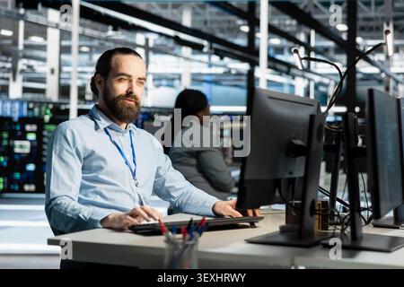 Data center programmer uses a computer to run diagnostics, update servers and check infrastructure performance. Stock Photo