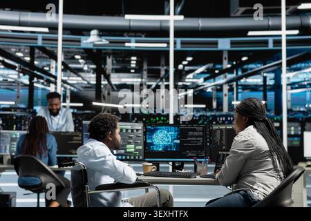 Developer with paraplegia and manager inspect a neural network data center, optimizing an inclusive server hub for AI workloads. Stock Photo