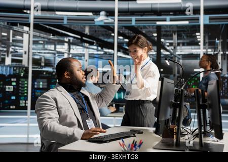 Delighted data center colleagues share a high five after improving system efficiency and completing AI implementation. Stock Photo