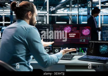 Computer scientist works with a computer workstation in a server farm to support artificial intelligence systems. Stock Photo
