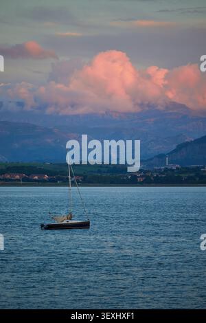 Sailing boat on background of beautiful landscape of sunset with colorful clouds and mountains in Santander, Spain. Stock Photo