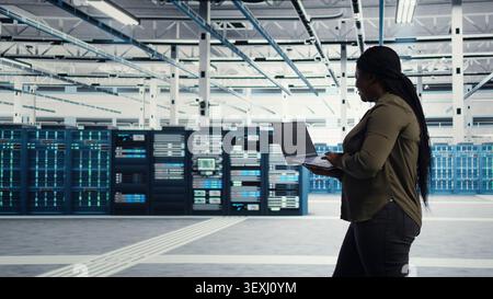 African american IT professional manages software updates in a server room to keep data center systems stable. Stock Photo