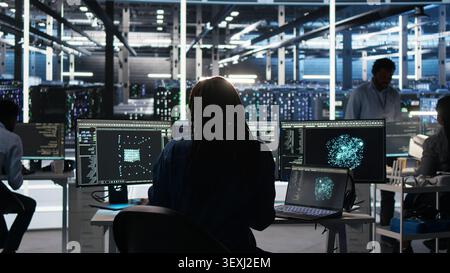 Data infrastructure center software programmer arriving at the office operates visual programming workflow to detect equipment operational performance issues. Stock Photo