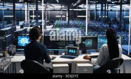 Colleagues celebrate in a server room after finishing neural network software development. Stock Photo