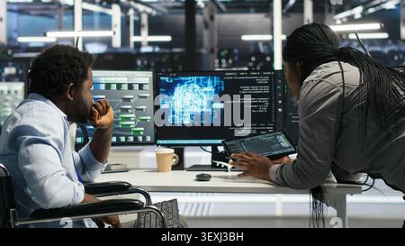 Data center specialist in wheelchair uses node tree AI software to analyze infrastructure and identify issues in a data center. Stock Photo