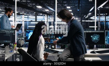 Senior engineer and trainee develop neural network software in a data center, using a PC to implement machine learning technology. Stock Photo