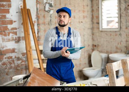 Focused contractor inspecting rooms and taking notes during renovation Stock Photo