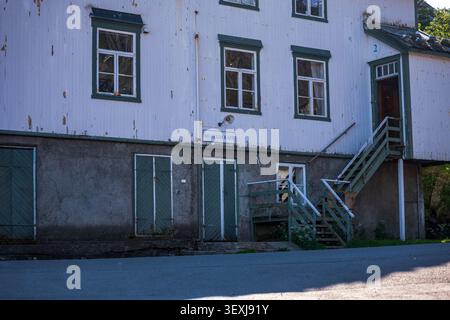 Weathered white wooden building with green trim in Lofoten. Historic museum structure showing aged corrugated metal siding, multiple Stock Photo