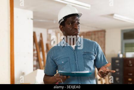 Strict building inspector standing with papers at construction site Stock Photo