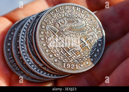 Engraving of dinosaur skeleton on souvenir dollar, stack of Hobo Nickel coins in hand Stock Photo