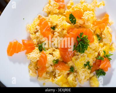 Tasty cooked omlette fried with salmon served at plate on table Stock Photo