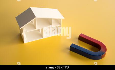 High angle view of an open white miniature house model layout and a classic horseshoe magnet on a bright yellow surface. Stock Photo