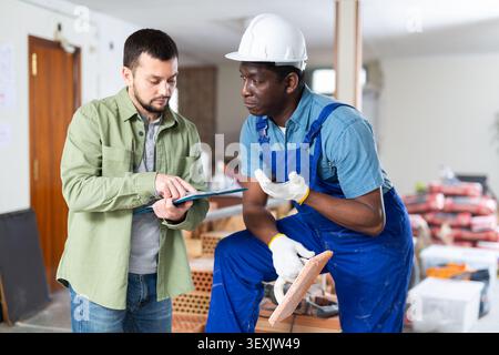 Engineer shows the estimate to a builder, explaining the working moments Stock Photo