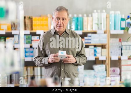 Older man reading label on box of medicine in drugstore Stock Photo