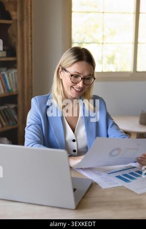 Businesswoman reviewing documents displaying charts and diagrams Stock Photo