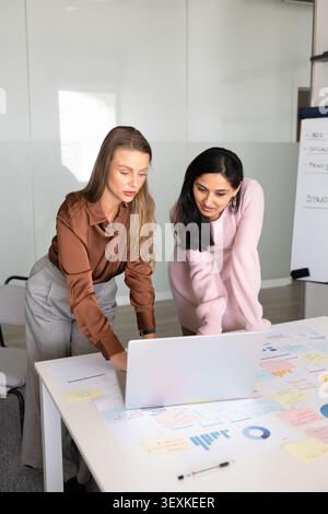 Colleagues examining marketing charts, reviewing reports and data on laptop Stock Photo