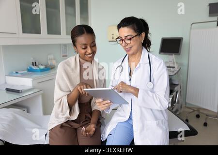 Happy senior doctor woman explaining electronic test results to patient Stock Photo