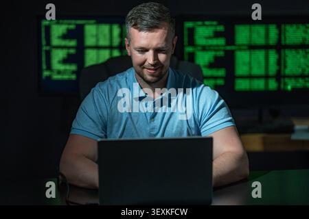Hacking programmer uses laptop computer. Hacking programmer writes code at night. Hacking programmer monitors server system. Hacking programmer Stock Photo