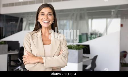 Woman in elegant suit posing for camera with arms crossed Stock Photo