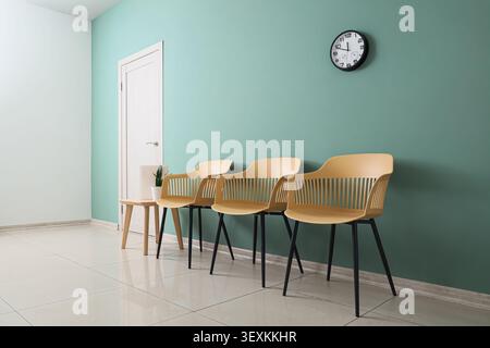 Empty waiting room with chairs and clock on wall Stock Photo