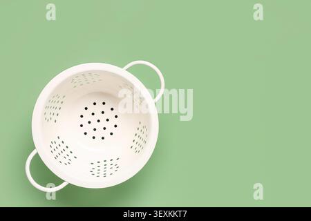 White colander on green background Stock Photo