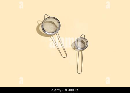 Two stainless steel tea strainers on beige background Stock Photo