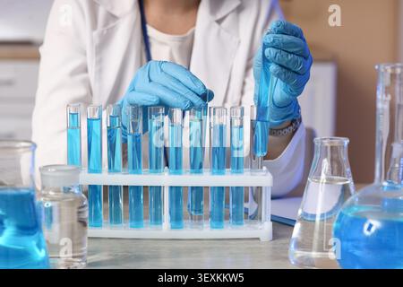 Scientist handling blue liquid in test tubes in laboratory Stock Photo