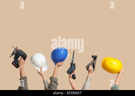 Hands with hardhats and construction tools on beige background Stock Photo