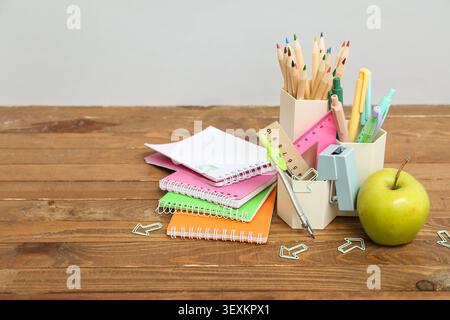 Pencil holder, notebooks, different school supplies and green apple on table against grey background Stock Photo