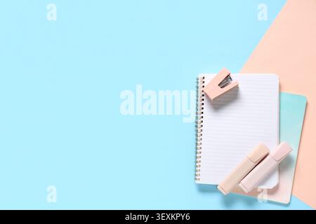 Notebooks, felt-tip pens and stapler on color background Stock Photo