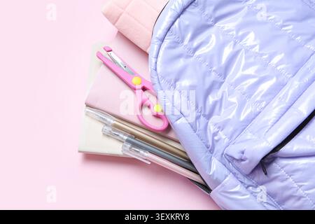 Lilac school backpack with stationery on pink background Stock Photo