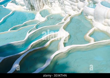 Bright blue mineral pools and white limestone terraces form a natural abstract landscape, creating a calm travel scene with clean lines, texture, and Stock Photo