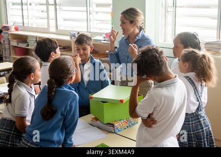 Elementary School Students Learning to Recycle Plastic Bottles with Teacher in Classroom Stock Photo