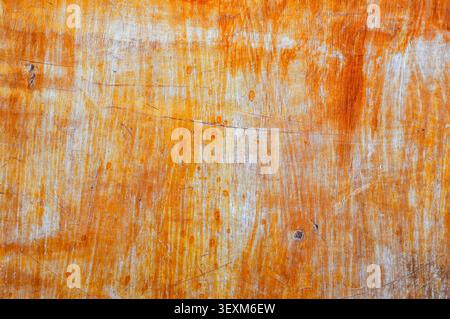 Abstract grunge background featuring a weathered orange and yellow painted wooden surface with scratches and rough texture Stock Photo