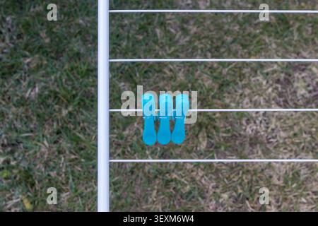 Vibrant Blue Clothespins on White Drying Rack Against Green Grass Stock Photo