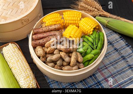 Boiled peanuts, corn cobs, Chinese yams and edamame pods in bamboo steamer Stock Photo