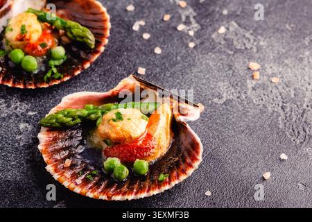 Cooked scallops with vegetables on a dark background Stock Photo