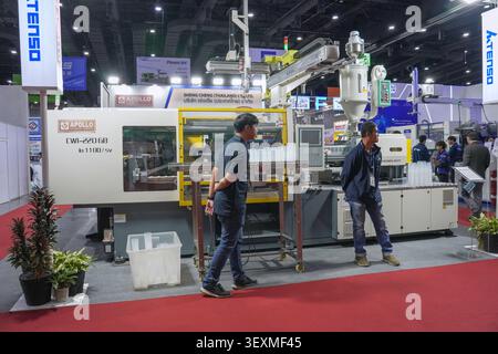 Bangkok, Thailand - June 17, 2026: Businessmen watching automated plastic cup production at Apollo injection molding machine display at Manufacturing Stock Photo