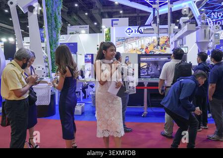 Bangkok, Thailand - June 17, 2026: Woman smiling while speaking with microphone at Haitian injection molding booth during Manufacturing Expo trade sho Stock Photo