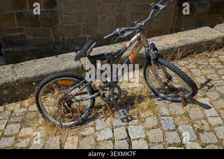 Rusty broken bicycle on cobblestone street. Monsanto, Portugal - June 22, 2025. Stock Photo