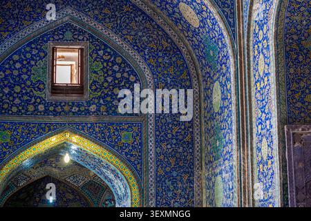Interior of the Shah Mosque in Isfahan, featuring arched walls completely covered with blue tiles and yellow floral motifs. A small rectangular window Stock Photo